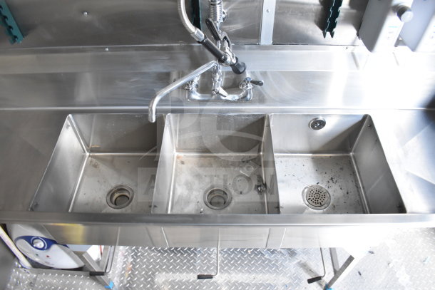 Stainless steel triple sink in a 2021 Rock Solid Cargo 28ft food trailer, featuring faucet and drain details.