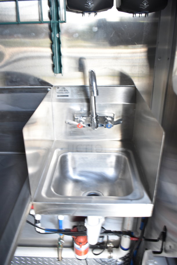 Stainless steel sink inside 2021 Rock Solid Cargo 28ft food trailer, featuring faucets and visible piping beneath.