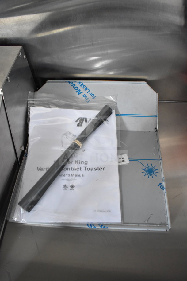 Owner's manual for the APW Wyott Vertical Contact Toaster, sealed in plastic with a black rod, in a new 2021 Rock Solid Cargo trailer.