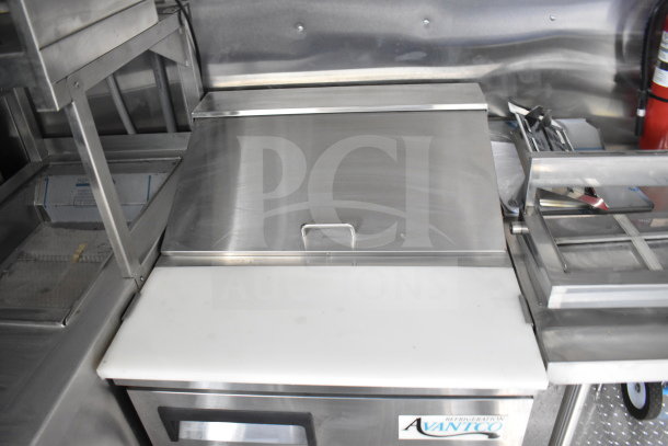 New 2021 Rock Solid Cargo food trailer interior with Avantco refrigeration, featuring stainless steel surfaces and storage.