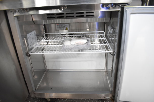 Interior of 2021 Rock Solid Cargo food trailer with refrigeration unit. Metal shelves, visible instructions, and package inside.