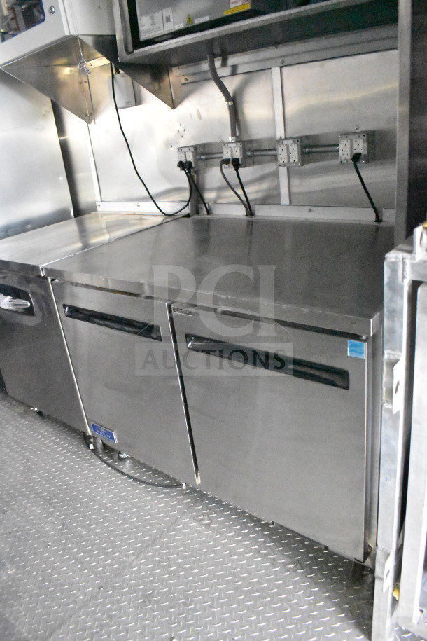 2021 Rock Solid Cargo 28ft food trailer interior with CaptiveAire hood, refrigeration units, and electrical outlets. New condition.