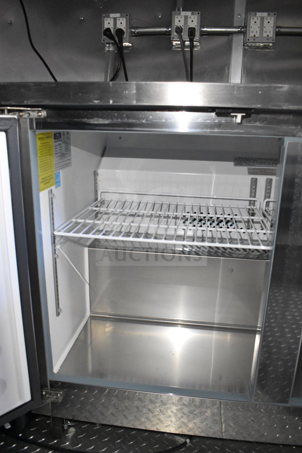 "Rock Solid Cargo 28ft food trailer interior, featuring refrigeration unit with metal shelves, electrical outlets visible."