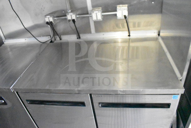 Rock Solid Cargo 28ft food trailer interior, features stainless steel counter and refrigeration unit with electrical outlets.
