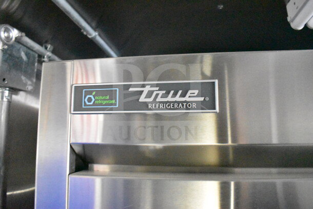 Stainless steel True refrigerator inside a 2021 Rock Solid Cargo commercial food trailer, featuring a natural refrigerant label.