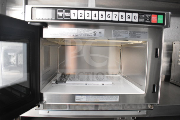Interior view of a Sharp commercial microwave within a 2021 Rock Solid Cargo food trailer, showing control panel and manual.