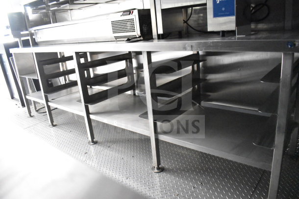 Stainless steel interior of a 2021 Rock Solid Cargo 28ft food trailer with shelves and refrigeration unit.