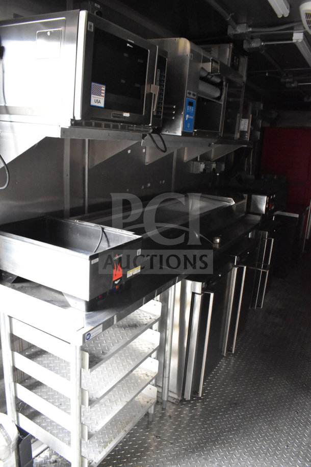 2021 Rock Solid Cargo 28ft food trailer interior, featuring a Henny Penny electric fryer, Taylor clamshell griddle, and CaptiveAire hood.