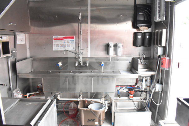 Rock Solid Cargo 28ft food trailer interior featuring stainless steel commercial sink, Ecolab sanitizer poster, dispensers, plumbing.