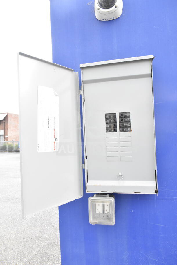 Electrical panel on a blue background, open to show breakers and a Siemens label, with a protective outlet cover below.