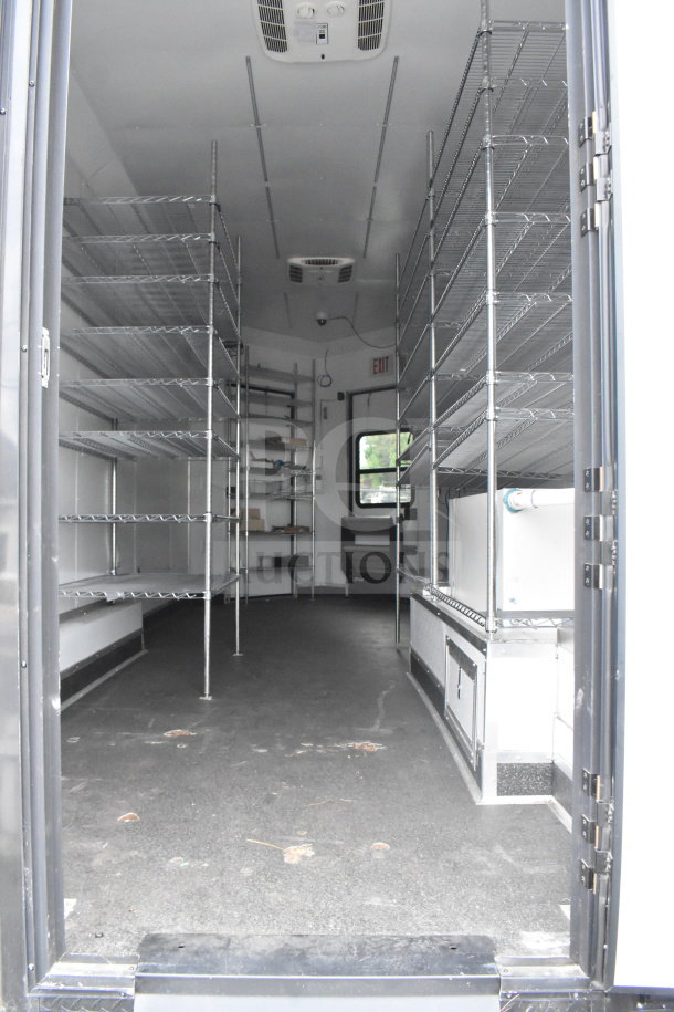 2020 Southern Dimensions Group 20ft all-black mobile commissary trailer; interior view with wire shelving, dual sinks, AC unit.
