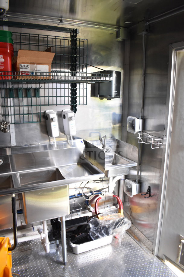 2021 Cruising Kitchens 8.5'x24' food trailer interior, featuring stainless steel sinks, shelving, and dispensers in excellent condition.