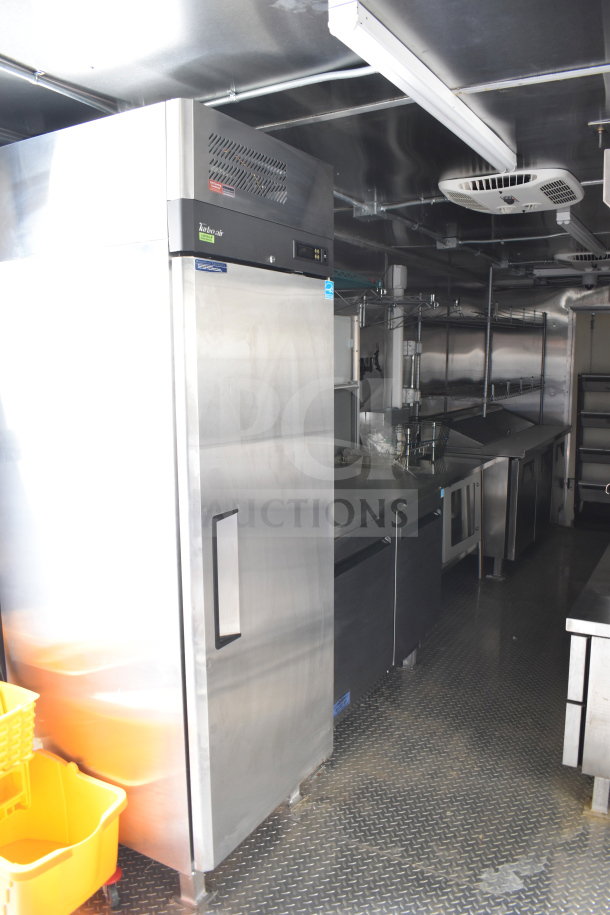2021 Cruising Kitchens 8.5'x24' food trailer interior with Turbo Air refrigerator, CaptiveAire grease hood, griddle, stainless steel counters.