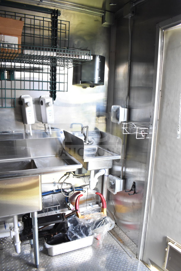 2021 Cruising Kitchens 8.5'x24' food trailer interior with dual sinks, storage racks, and stainless steel fixtures.