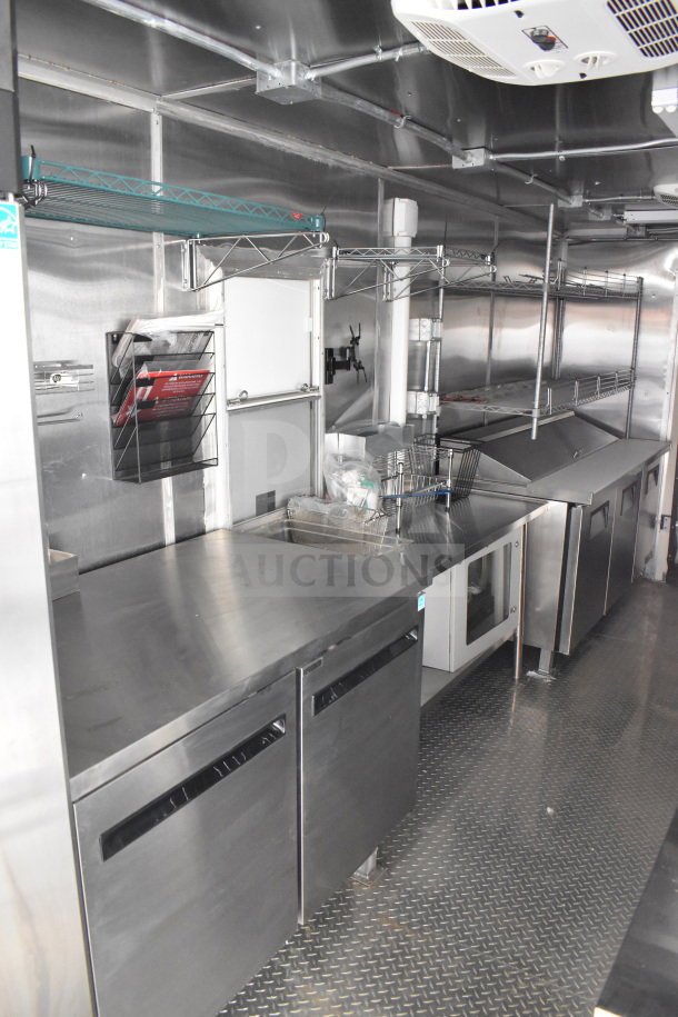 2021 Cruising Kitchens 8.5'x24' food trailer interior with CaptiveAire grease hood, refrigeration, griddle, and stainless steel surfaces.