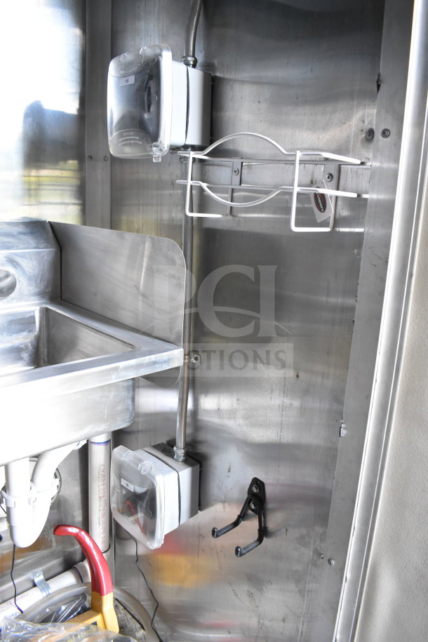 2021 Cruising Kitchens 8.5'x24' food trailer interior, featuring stainless steel walls, sink, and mounted accessories.
