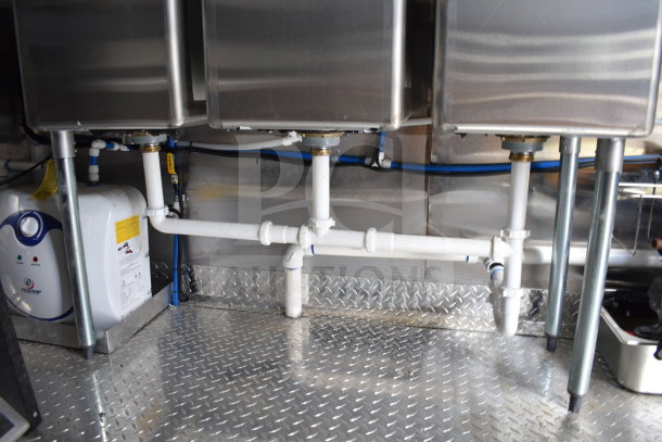 2021 Cruising Kitchens food trailer plumbing setup with dual sinks and utility pipes on diamond plate flooring.