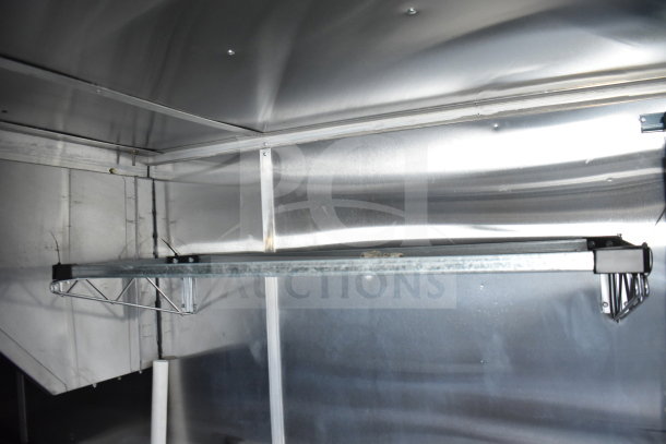Interior of a 2021 Cruising Kitchens food trailer showcasing metal shelving and CaptiveAire grease hood.