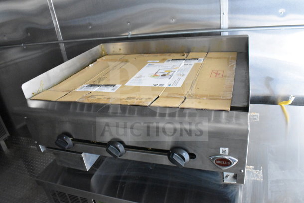 2021 Cruising Kitchens food trailer interior showing Wells griddle, stainless steel finish, cardboard cover, control knobs.