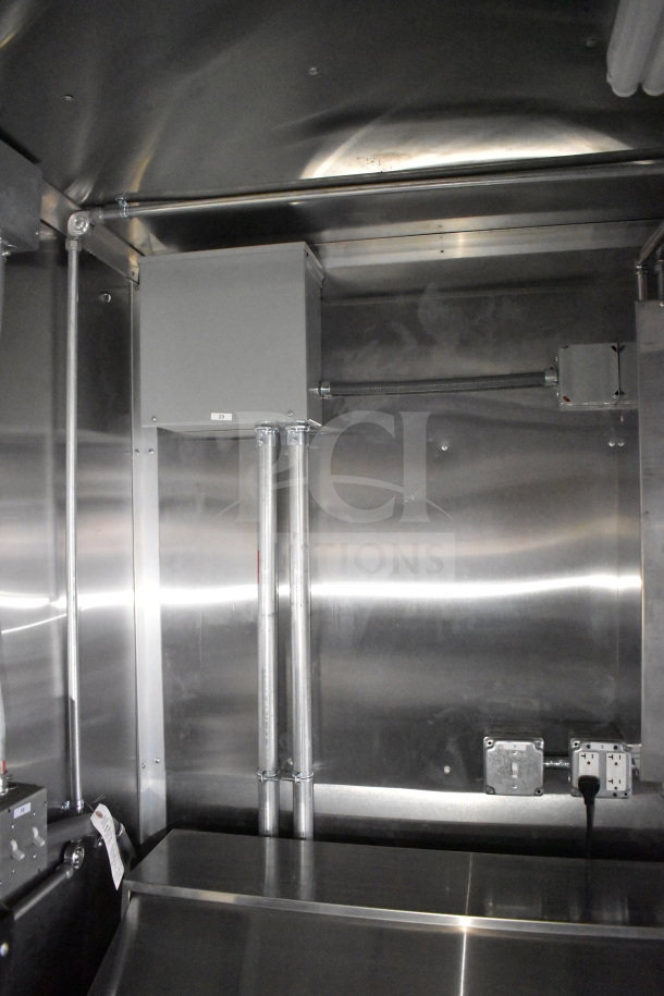 Interior of 2021 Cruising Kitchens food trailer with stainless steel walls, electrical outlets, and control box visible.