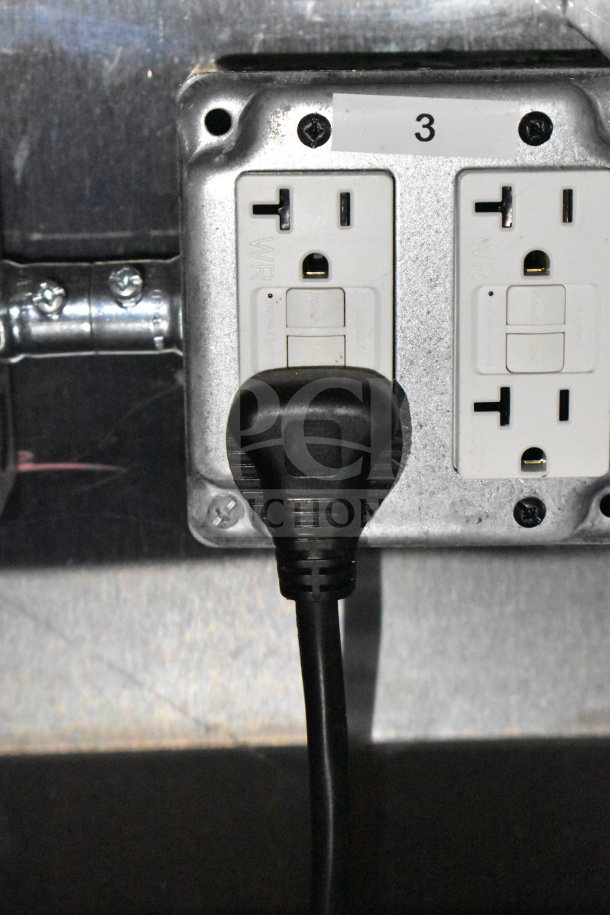 Two electrical outlets labeled "3," with a black power cord plugged into one outlet.