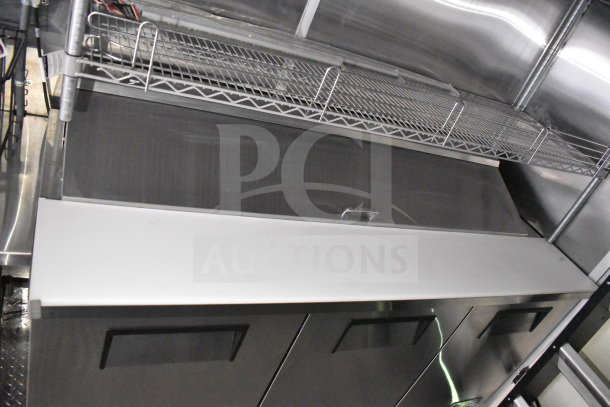 2021 Cruising Kitchens 8.5'x24' food trailer interior with CaptiveAire grease hood, stainless steel surfaces, and storage rack.