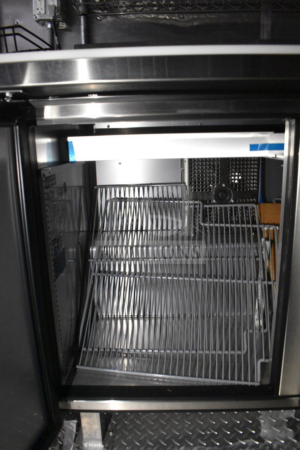 Interior view of 2021 Cruising Kitchens food trailer, showcasing stainless steel shelving and refrigeration unit.