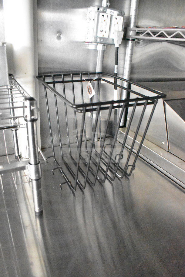 Interior view of a 2021 Cruising Kitchens food trailer with metal shelving and electrical outlets, highlighting the built-in infrastructure.