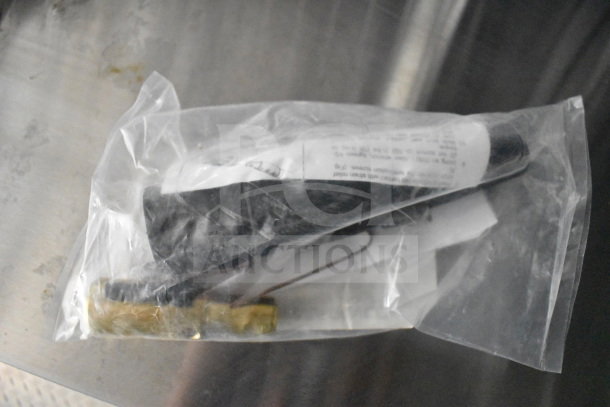 A plastic bag containing unidentified components with a label featuring printed text, placed on a metallic surface.