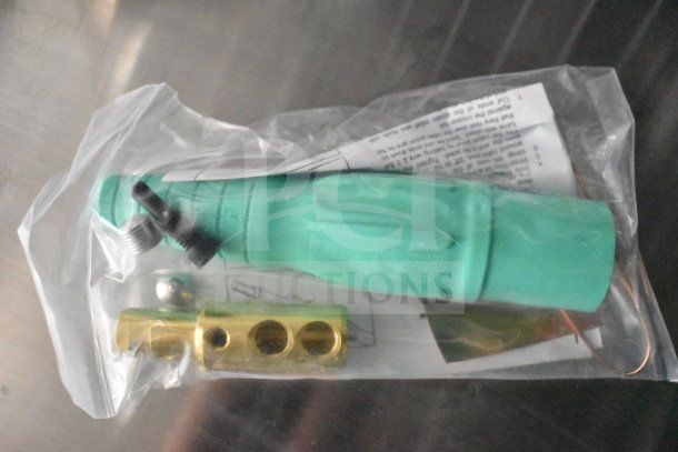 Plastic-wrapped accessory kit including a green handle, brass connector, and two black screws. Instructions partially visible.