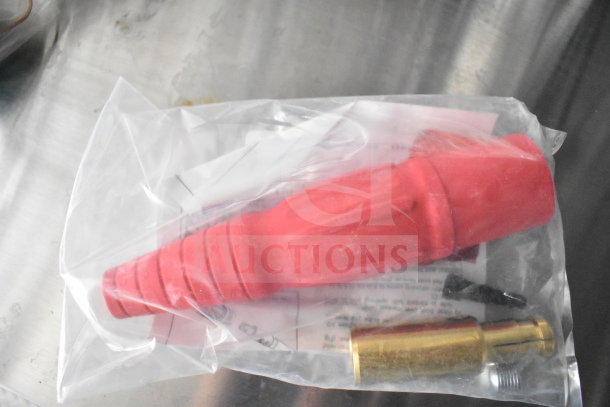 Plastic bag containing a red protective cap, a brass fitting, and a small metal screw, placed on a metallic surface.
