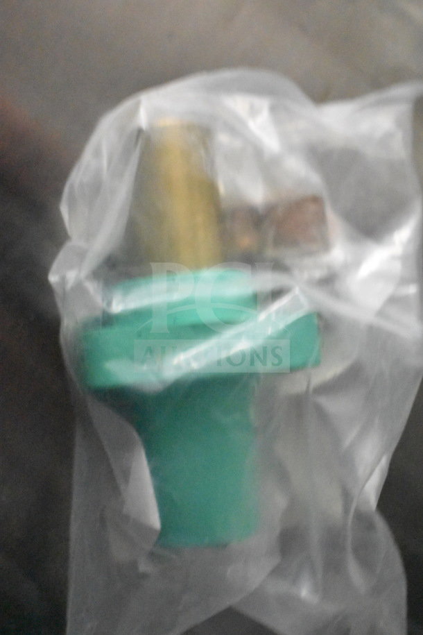 A close-up of a packaged green mechanical part with metal fittings, wrapped in clear plastic for protection.