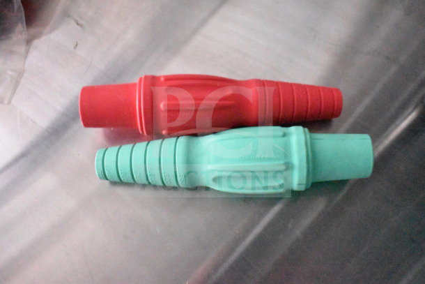 Two colored plastic fittings, red and green, with ribbed grooves and embossed text, lay on a metallic surface.