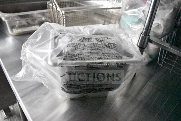 Plastic-covered container on a stainless steel surface inside 2021 Cruising Kitchens food trailer; protective packaging visible.