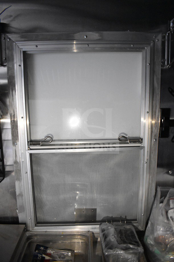 Interior of 2021 Cruising Kitchens food trailer, showing stainless steel construction and service window.