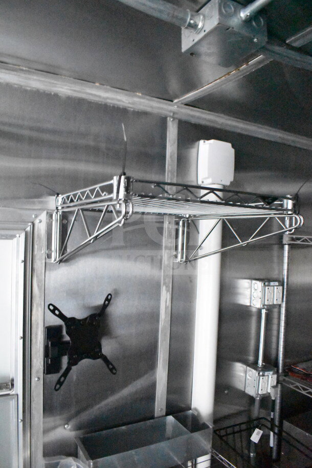 2021 Cruising Kitchens 8.5'x24' food trailer interior, showcasing a metal shelving unit and electrical fittings.