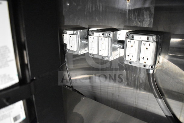 Electrical outlets inside 2021 Cruising Kitchens 8.5'x24' food trailer, featuring labeled panels and stainless steel wall.