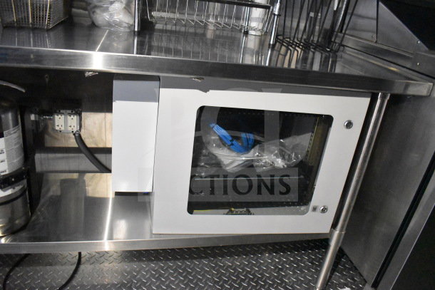 2021 Cruising Kitchens food trailer interior showing stainless steel counters, suppression system, and storage compartments.
