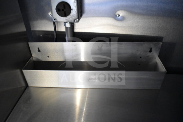2021 Cruising Kitchens food trailer interior, featuring a stainless steel wall-mounted shelf and electrical outlet above.