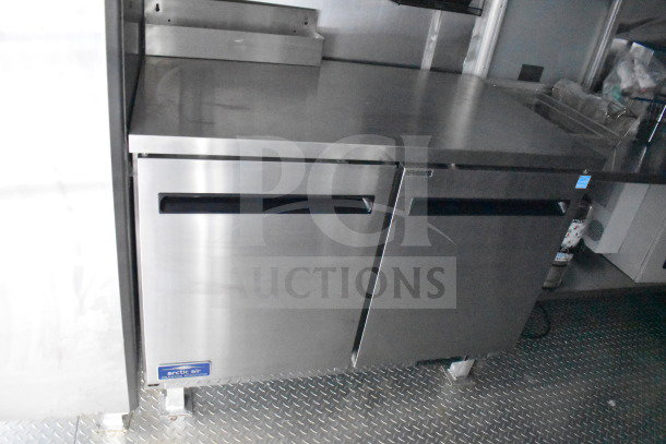2021 Cruising Kitchens 8.5'x24' food trailer interior; features stainless steel Arctic Air commercial refrigerator unit.