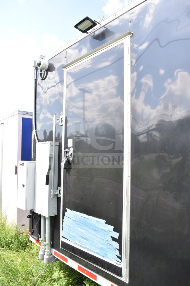 2021 Cruising Kitchens 8.5'x24' food trailer, black exterior, visible rear access door, electrical components mounted.