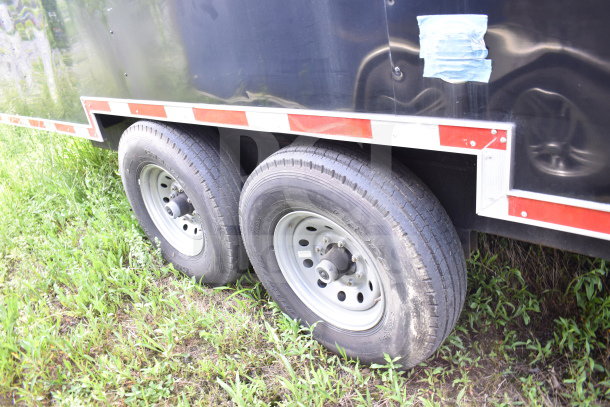 2021 Cruising Kitchens 8.5'x24' food trailer wheels, featuring dual axles and red reflective tape on black exterior.