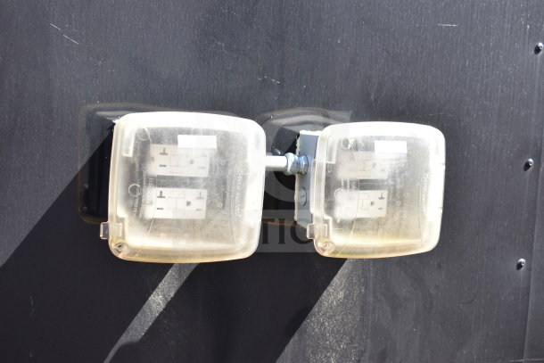 Dual electrical power outlet with protective covers on a food trailer exterior, ensuring safety and functionality.