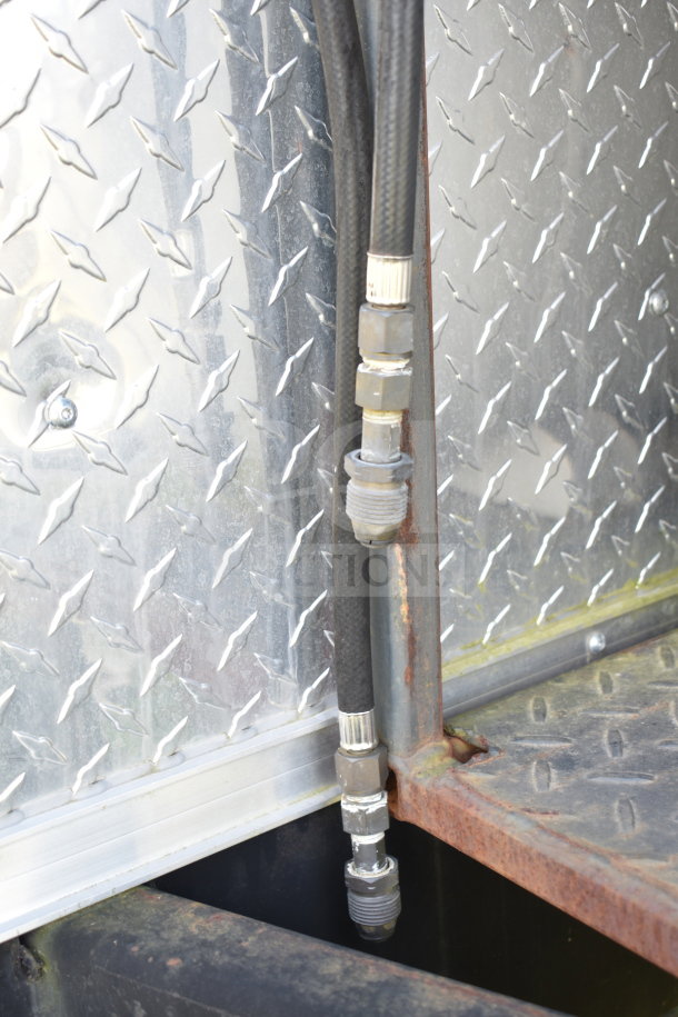Close-up of a 2021 Cruising Kitchens food trailer's metal exterior with visible hoses and connections.