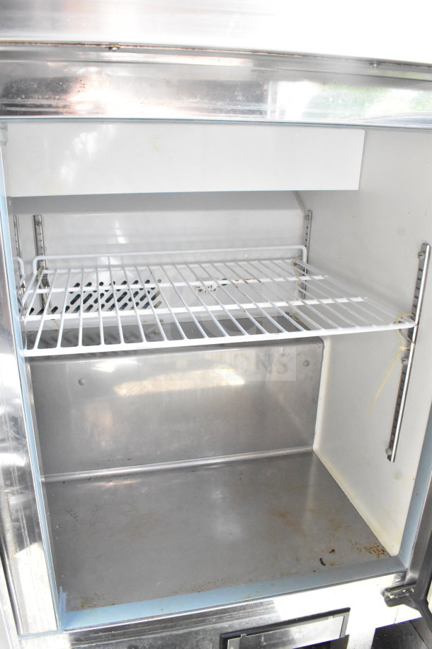 Empty refrigerator interior of 2020 Diamond Cargo 8.5'x24' Food Trailer, showing wire shelving and stainless steel surfaces.