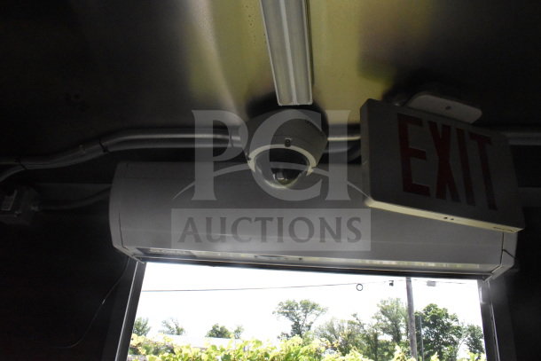Interior view of 2020 Diamond Cargo 8.5'x24' food trailer, showing ceiling with security camera, fluorescent light, and exit sign.