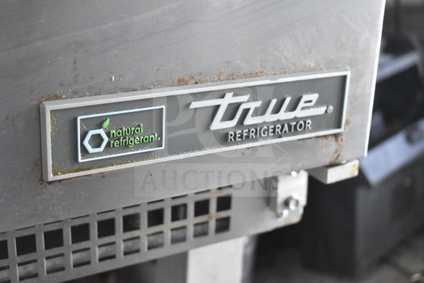 Close-up of a True refrigerator label with "natural refrigerant" logo, showing some rust and wear on the metal surface.