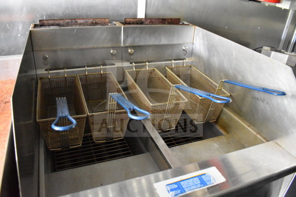 Industrial-grade deep fryer with four baskets, blue handles, stainless steel finish, inside a 2020 Diamond Cargo food trailer.