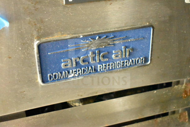 Arctic Air commercial refrigerator label on stainless steel, showing wear and rust spots.