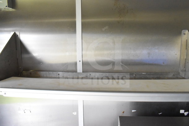 Interior view of 2020 Diamond Cargo 8.5'x24' food trailer, showing metal shelves and walls, some wear visible. VIN: 53NBE2422L1083693.